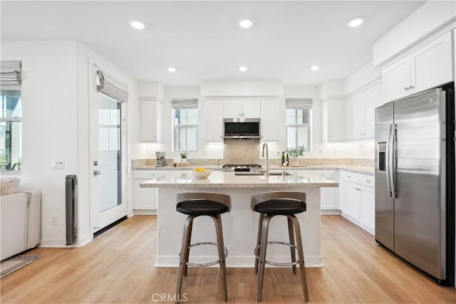 kitchen with a kitchen island, white cabinetry, a breakfast bar area, light hardwood / wood-style floors, and stainless steel appliances