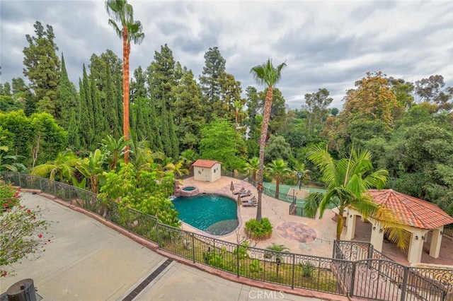 view of property's community with a swimming pool, a hot tub, a patio, and fence