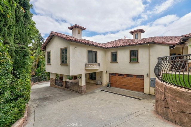 rear view of house featuring stucco siding, an attached garage, driveway, and a tiled roof