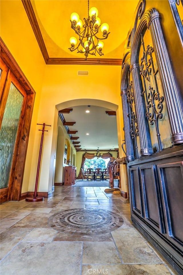 entryway with a chandelier, crown molding, and a towering ceiling