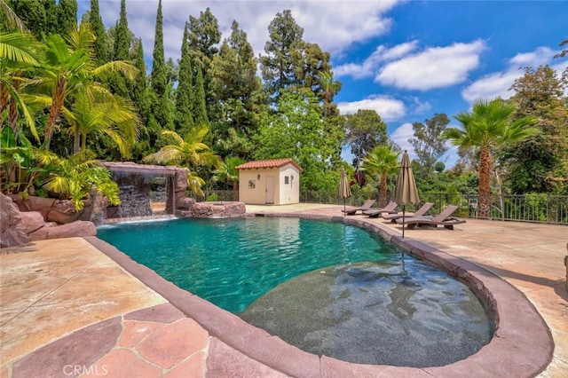 view of pool featuring pool water feature, an outbuilding, and a patio