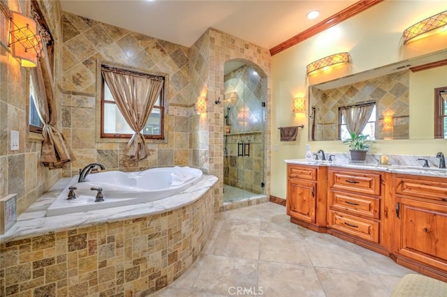 bathroom with a sink, double vanity, a shower stall, a garden tub, and ornamental molding