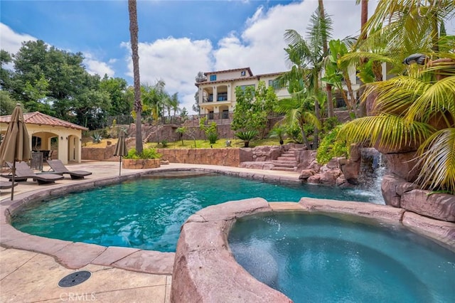 view of pool with a patio area, a pool with connected hot tub, and fence