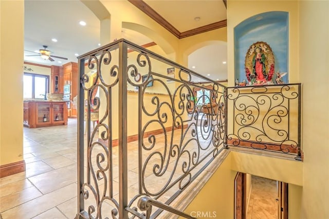 stairway with ceiling fan and crown molding