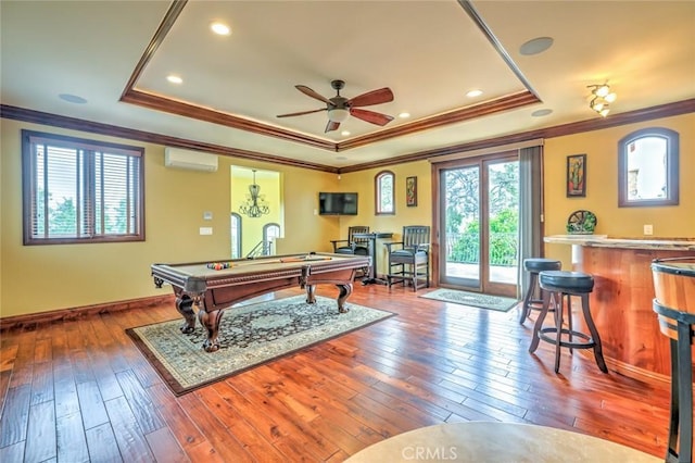 game room featuring a tray ceiling, an AC wall unit, and ornamental molding