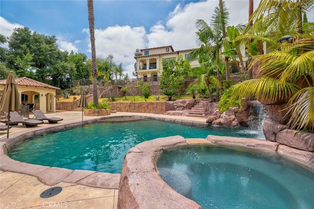 view of pool featuring a patio area, a pool with connected hot tub, and fence