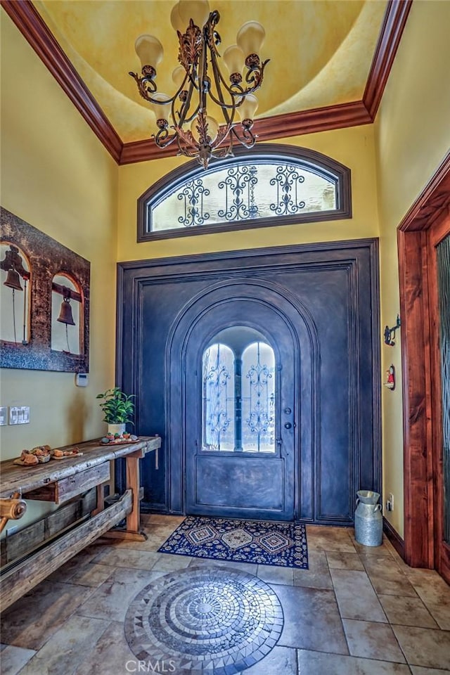 foyer entrance featuring a healthy amount of sunlight, ornamental molding, and a notable chandelier