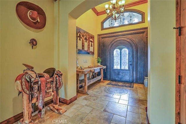 entrance foyer with arched walkways, stone tile flooring, baseboards, and an inviting chandelier