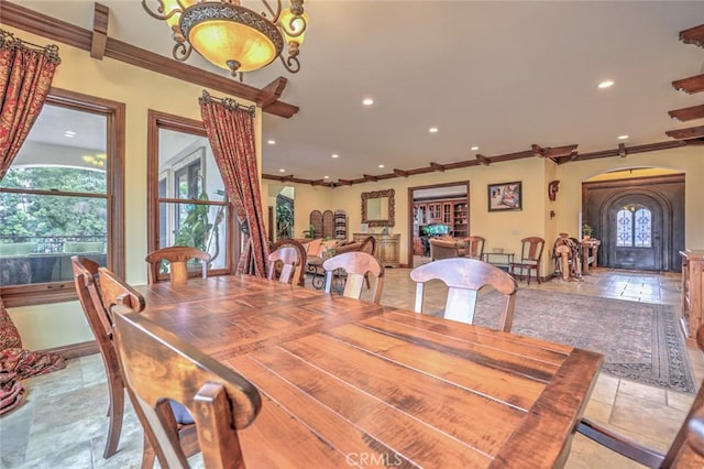 dining area featuring stone tile floors, arched walkways, recessed lighting, and ornamental molding