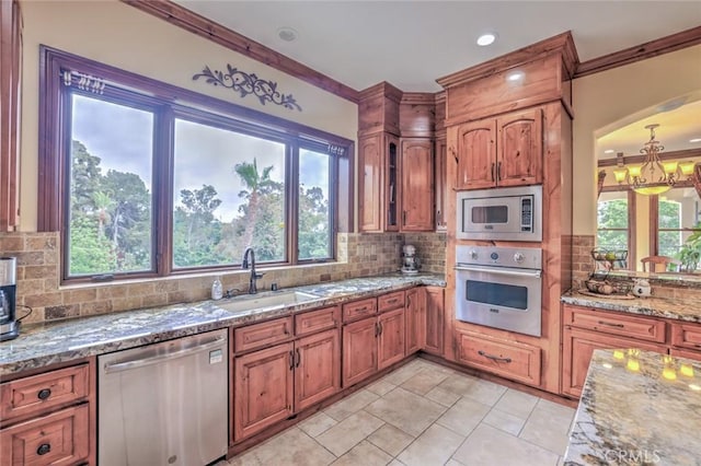 kitchen with brown cabinetry, a sink, appliances with stainless steel finishes, and tasteful backsplash