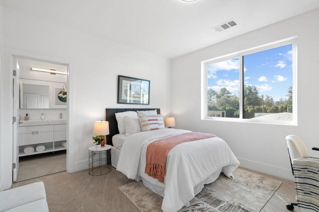 bedroom featuring light carpet and connected bathroom