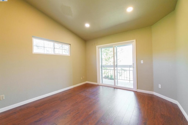 spare room with dark wood-type flooring and vaulted ceiling