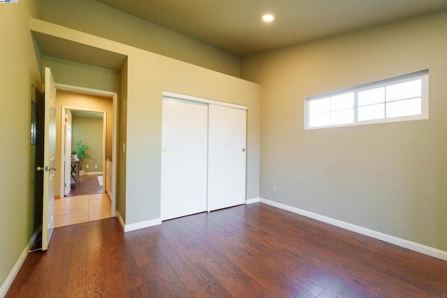 unfurnished bedroom with dark wood-type flooring and a closet