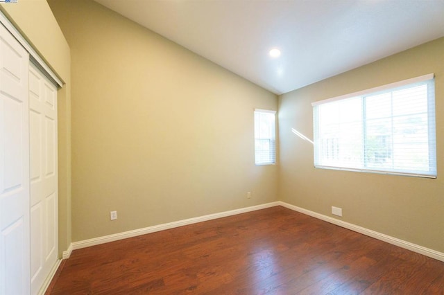 unfurnished bedroom with dark hardwood / wood-style flooring, vaulted ceiling, and a closet