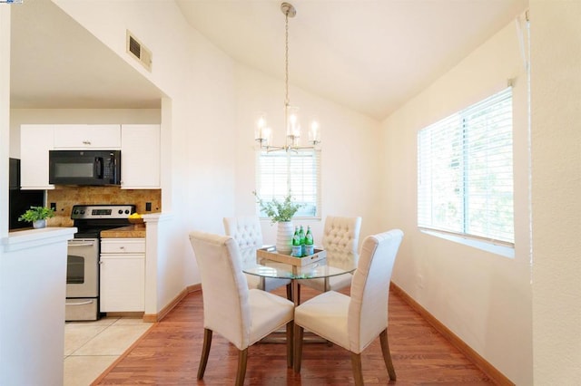 dining space with vaulted ceiling, plenty of natural light, and a chandelier