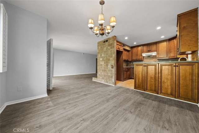 kitchen with backsplash, light hardwood / wood-style flooring, hanging light fixtures, and a notable chandelier