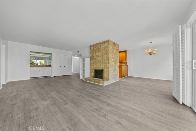 unfurnished living room with a chandelier, a fireplace, and light hardwood / wood-style flooring