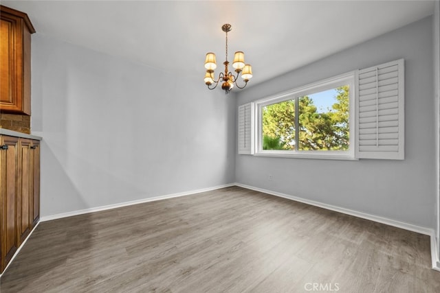 unfurnished dining area with wood-type flooring and an inviting chandelier