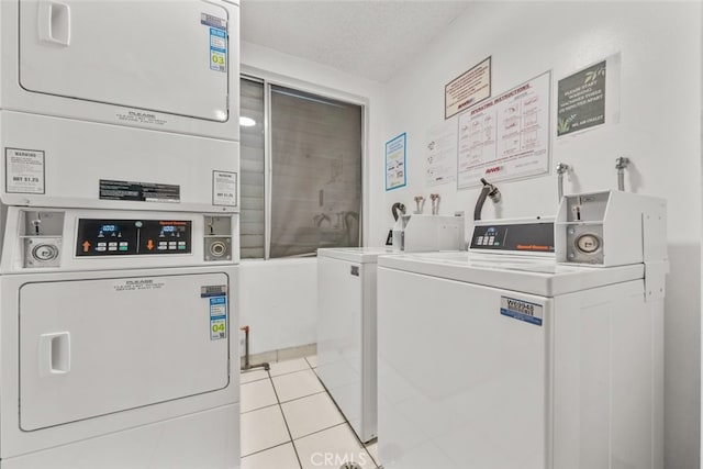 laundry area with a textured ceiling, washer and clothes dryer, stacked washing maching and dryer, and light tile patterned flooring