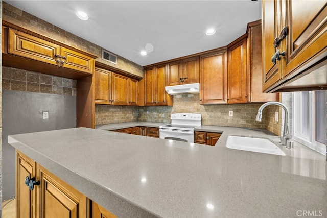 kitchen with electric stove, kitchen peninsula, sink, and tasteful backsplash