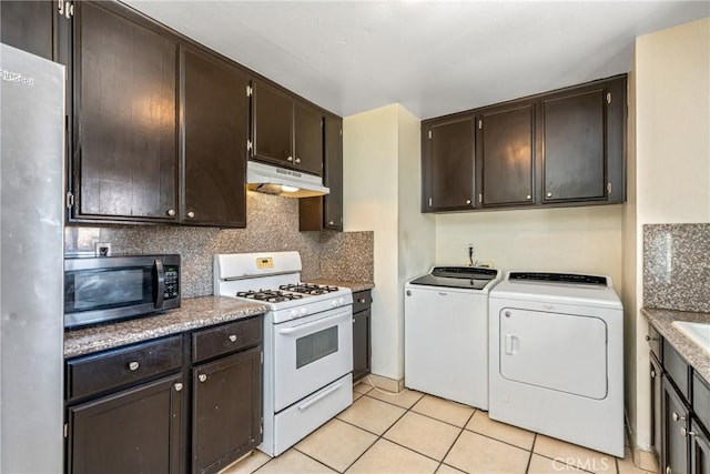 kitchen featuring appliances with stainless steel finishes, tasteful backsplash, light tile patterned floors, dark brown cabinets, and washer and clothes dryer