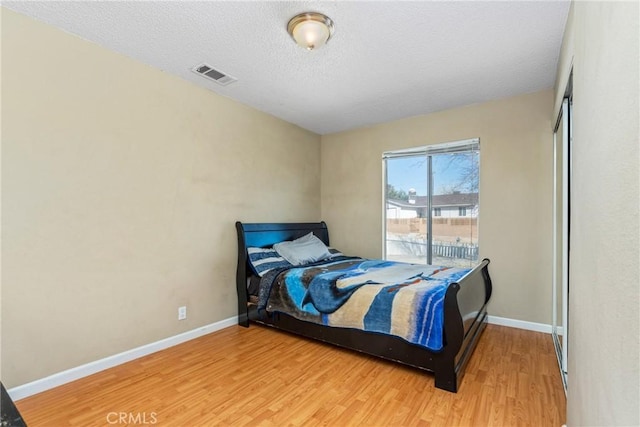 bedroom with hardwood / wood-style flooring, access to outside, and a textured ceiling