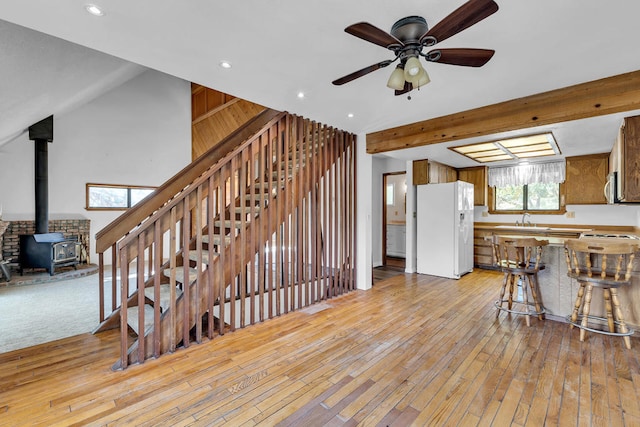 interior space with sink, beamed ceiling, a wood stove, and hardwood / wood-style flooring