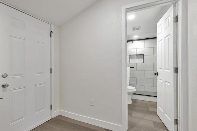 bathroom with hardwood / wood-style flooring, toilet, and walk in shower