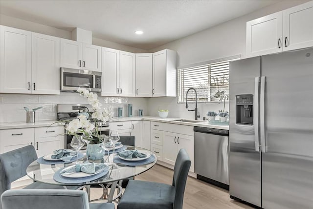 kitchen featuring sink, light hardwood / wood-style flooring, stainless steel appliances, and white cabinets