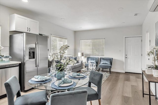 dining area with light hardwood / wood-style flooring and an AC wall unit