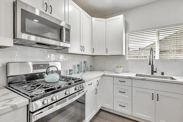 kitchen with light stone counters, sink, stainless steel appliances, and white cabinets