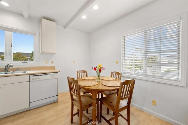 dining room with sink, beamed ceiling, and light hardwood / wood-style flooring