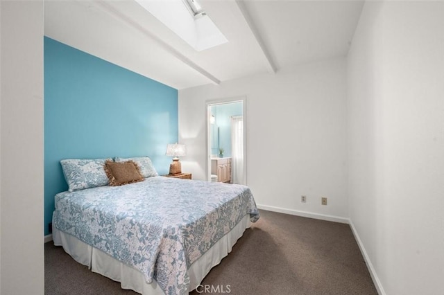 bedroom with dark colored carpet, ensuite bathroom, beamed ceiling, and a skylight