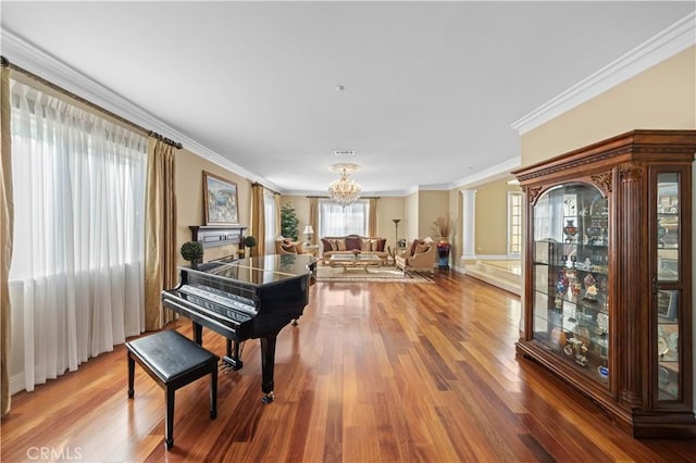 misc room featuring hardwood / wood-style floors, ornamental molding, a chandelier, and decorative columns