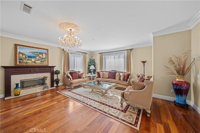 living room featuring dark hardwood / wood-style floors, crown molding, a chandelier, and a fireplace