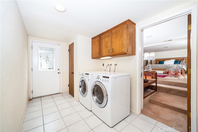 washroom featuring light tile patterned floors, washing machine and clothes dryer, and cabinets