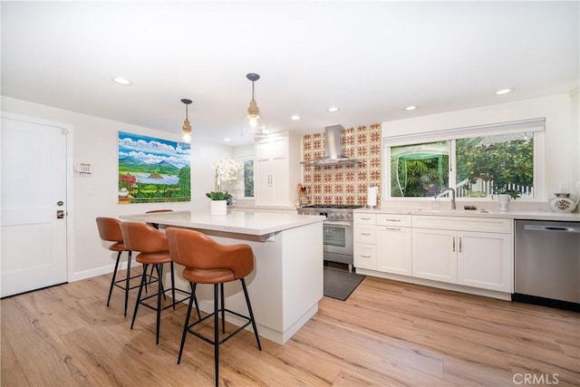 kitchen featuring white cabinetry, a center island, stainless steel appliances, and wall chimney exhaust hood