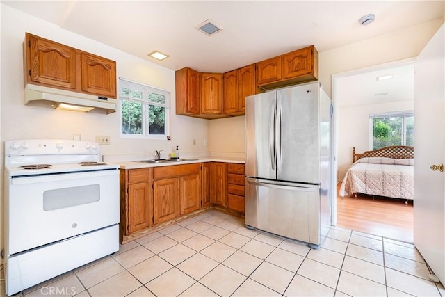 kitchen with light tile patterned flooring, a wealth of natural light, white electric range oven, and stainless steel refrigerator