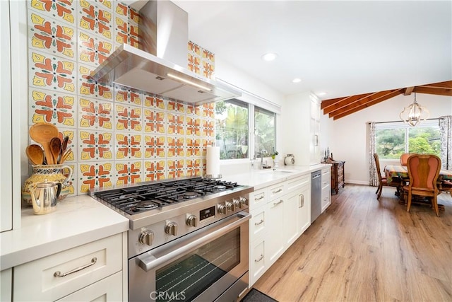 kitchen featuring island exhaust hood, stainless steel appliances, lofted ceiling, a chandelier, and sink