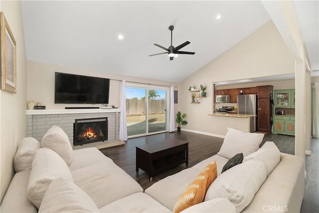 living room with dark wood-type flooring, ceiling fan, high vaulted ceiling, and a brick fireplace