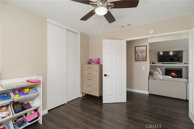 game room featuring dark hardwood / wood-style flooring, a brick fireplace, and ceiling fan