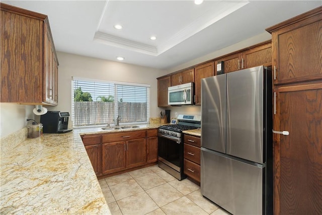 kitchen with a raised ceiling, sink, light tile patterned floors, stainless steel appliances, and light stone countertops