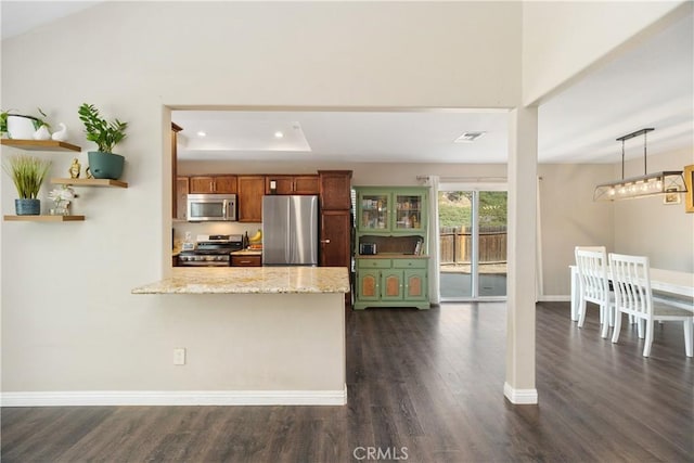 kitchen featuring stainless steel appliances, light stone countertops, dark hardwood / wood-style flooring, decorative light fixtures, and kitchen peninsula