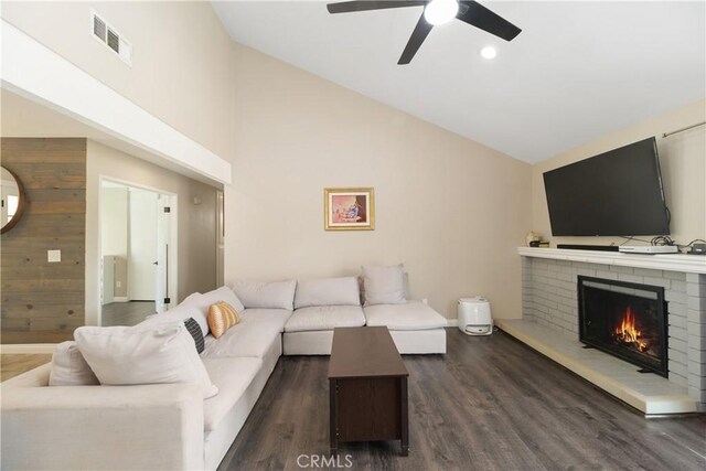 living room featuring a brick fireplace, dark wood-type flooring, high vaulted ceiling, and ceiling fan