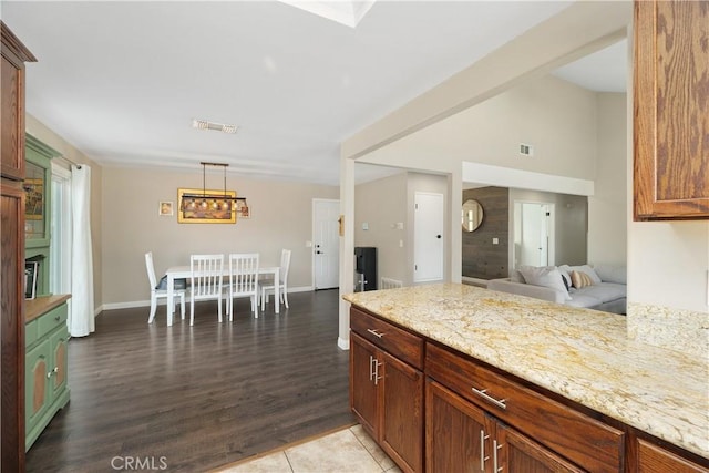 kitchen with pendant lighting, wood-type flooring, kitchen peninsula, and light stone counters