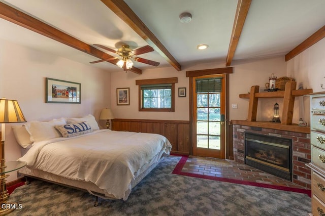 bedroom featuring beamed ceiling, carpet, wainscoting, a brick fireplace, and wooden walls