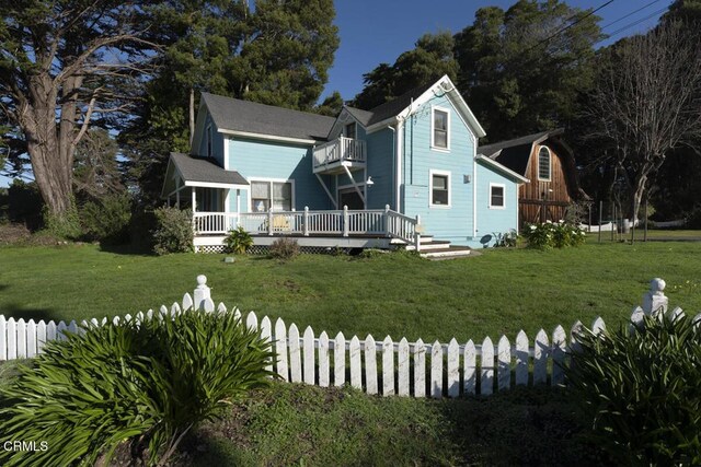 view of front of house featuring a balcony, fence, and a front lawn
