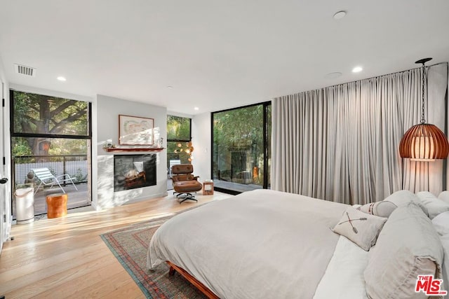 bedroom featuring multiple windows, light hardwood / wood-style flooring, floor to ceiling windows, and access to outside