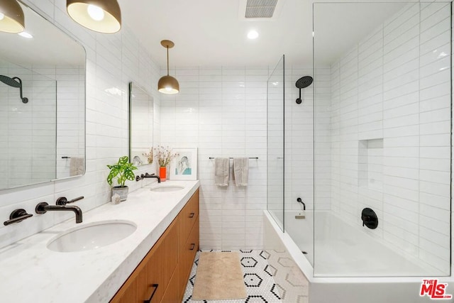 bathroom with tiled shower / bath, vanity, tile patterned flooring, and tile walls