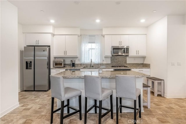 kitchen with stainless steel appliances, sink, white cabinets, and a center island